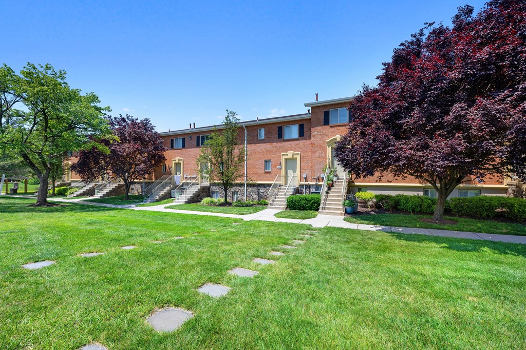 a large brick building with stairs and grass and trees at Gainsborough Court Apartments, Virginia