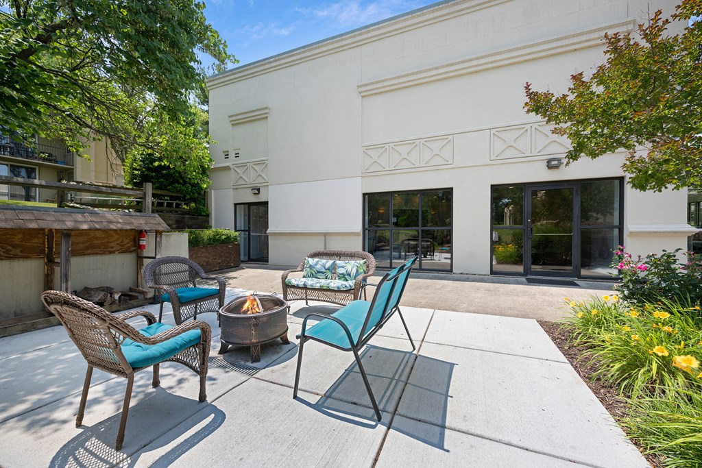 a patio with chairs and a fire pit and a building in the background at Stuart Woods* Apartments, Virginia