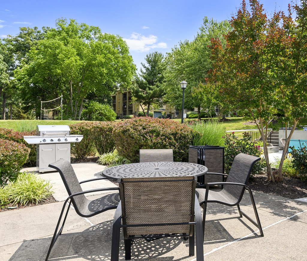 a patio with a table and chairs and a grill at Stuart Woods* Apartments, Herndon