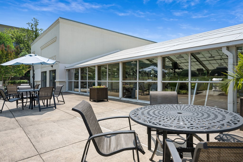 a patio with tables and chairs and a building in the background at Stuart Woods* Apartments, Herndon, VA