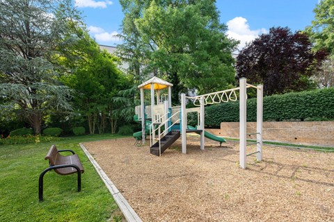 A playground with a slide, swing set, and a bench.
