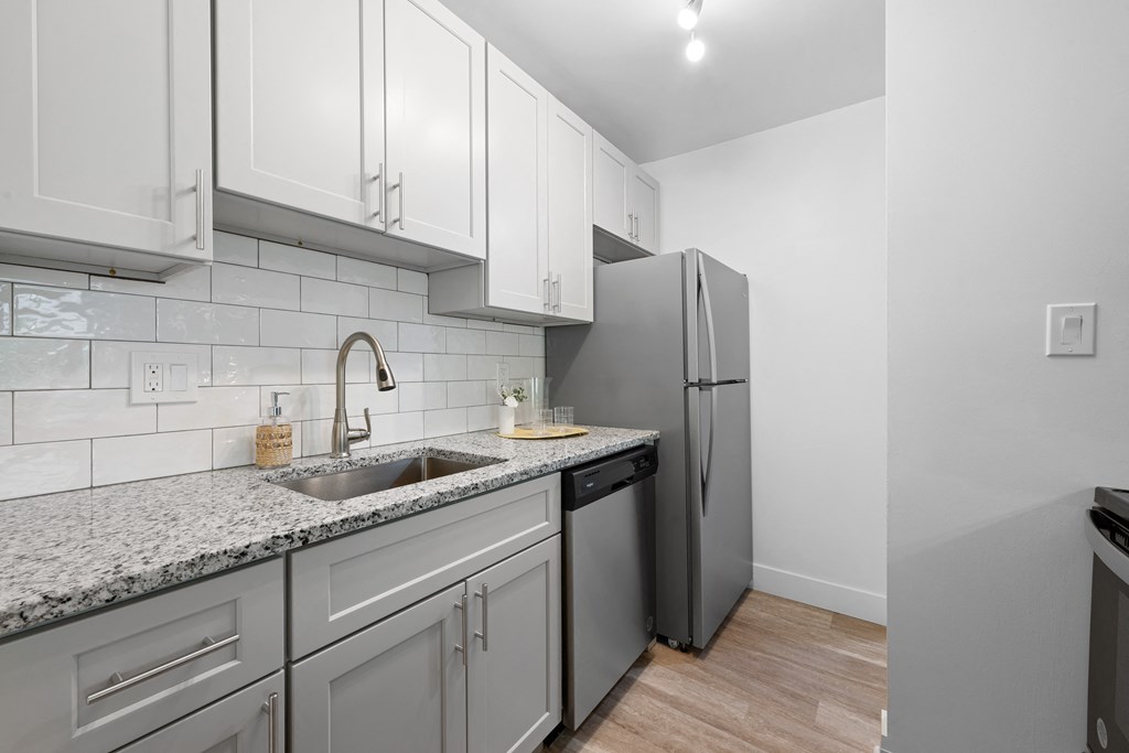 a kitchen with white cabinets and a sink and a refrigerator at Gainsborough Court Apartments, Virginia, 22030