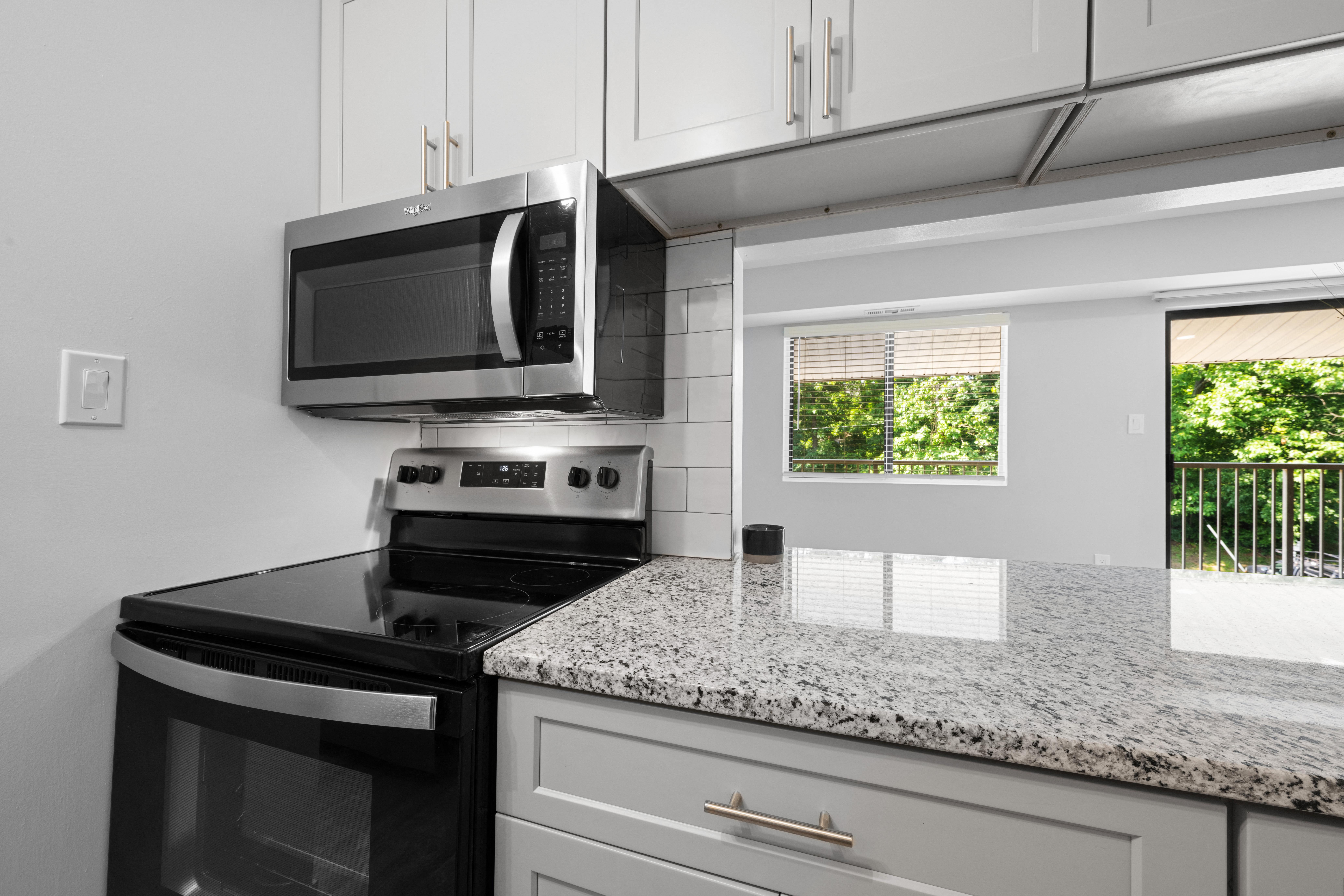 A kitchen with a black stove top oven and a black microwave above it.