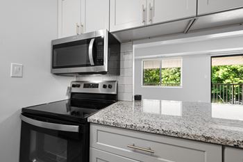 an updated kitchen with granite counter tops and black appliances at Gainsborough Court Apartments, Fairfax