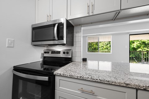 an updated kitchen with granite counter tops and black appliances