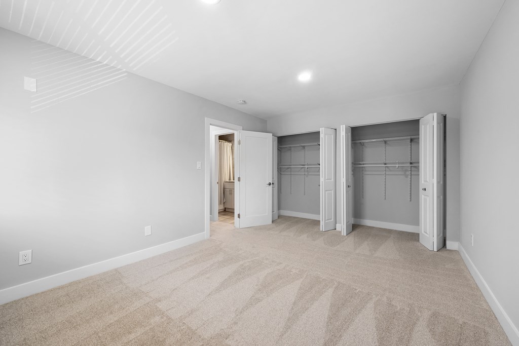 a living room with white walls and carpet and a closet with doors at Gainsborough Court Apartments, Fairfax, 22030