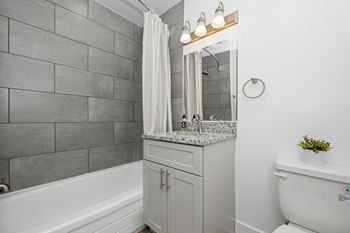 a bathroom with a sink and a toilet and a bath tub at Gainsborough Court Apartments, Fairfax, VA