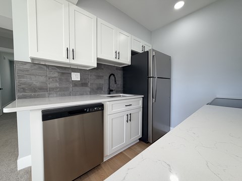 A kitchen with white cabinets and a black refrigerator.