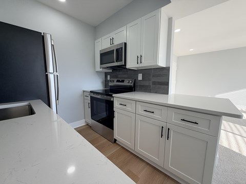 A kitchen with white cabinets and a marble countertop.