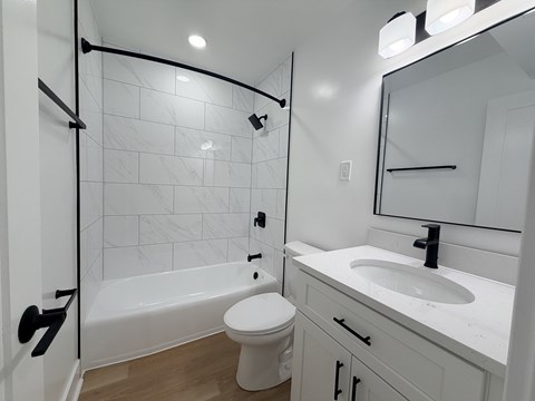 A white bathroom with a toilet, sink, and a shower with a glass door.