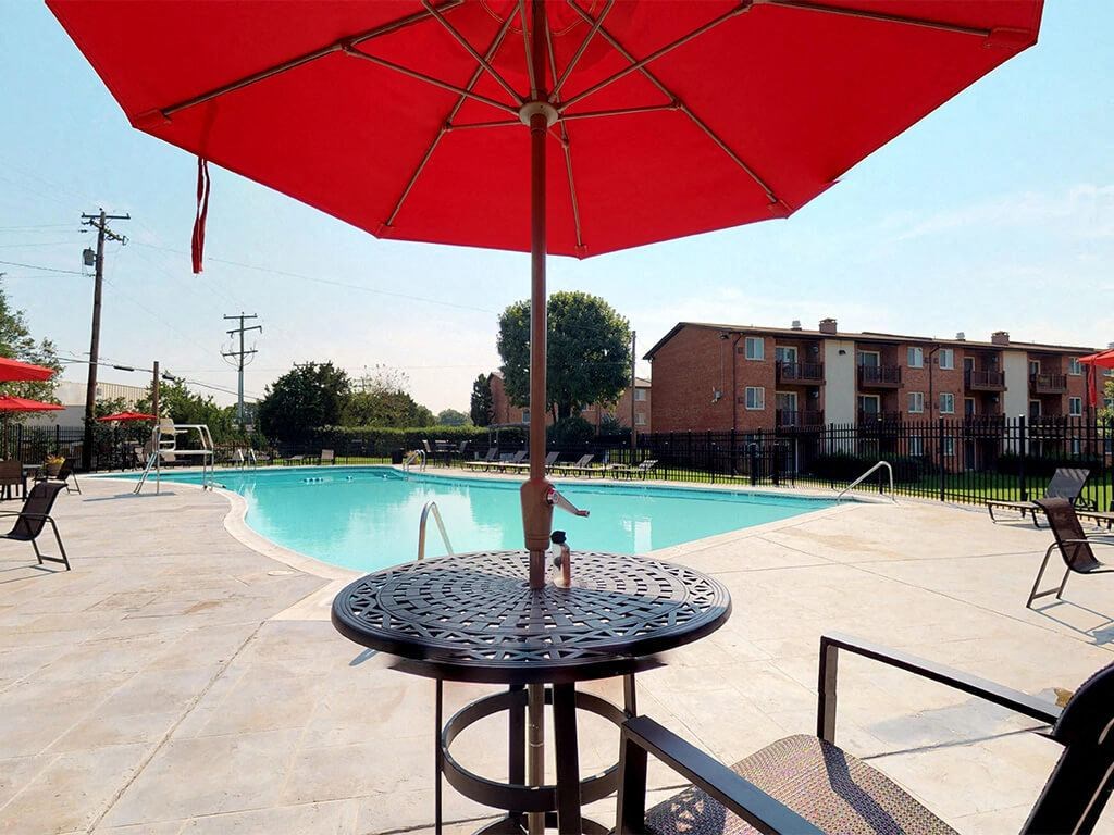 Large red umbrella with table near side of the pool at Rose Hill Apartments, Alexandria, VA, 22310