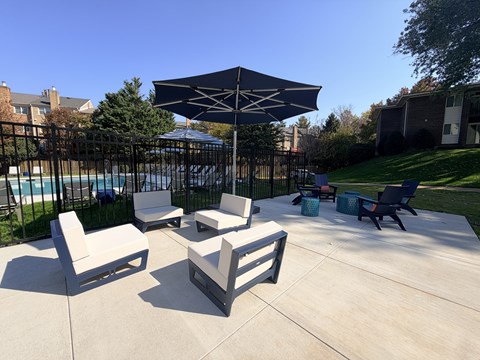 A patio with a table, chairs and an umbrella.