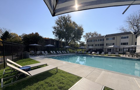 A sunny day at the pool with a bench and umbrellas.