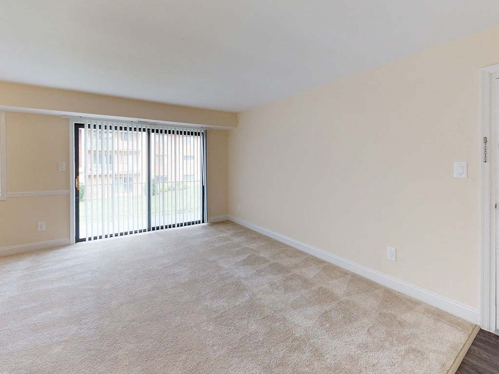 View of large living room area in apartment building with carpeting at Gainsborough Court Apartments, Fairfax, VA, 22030