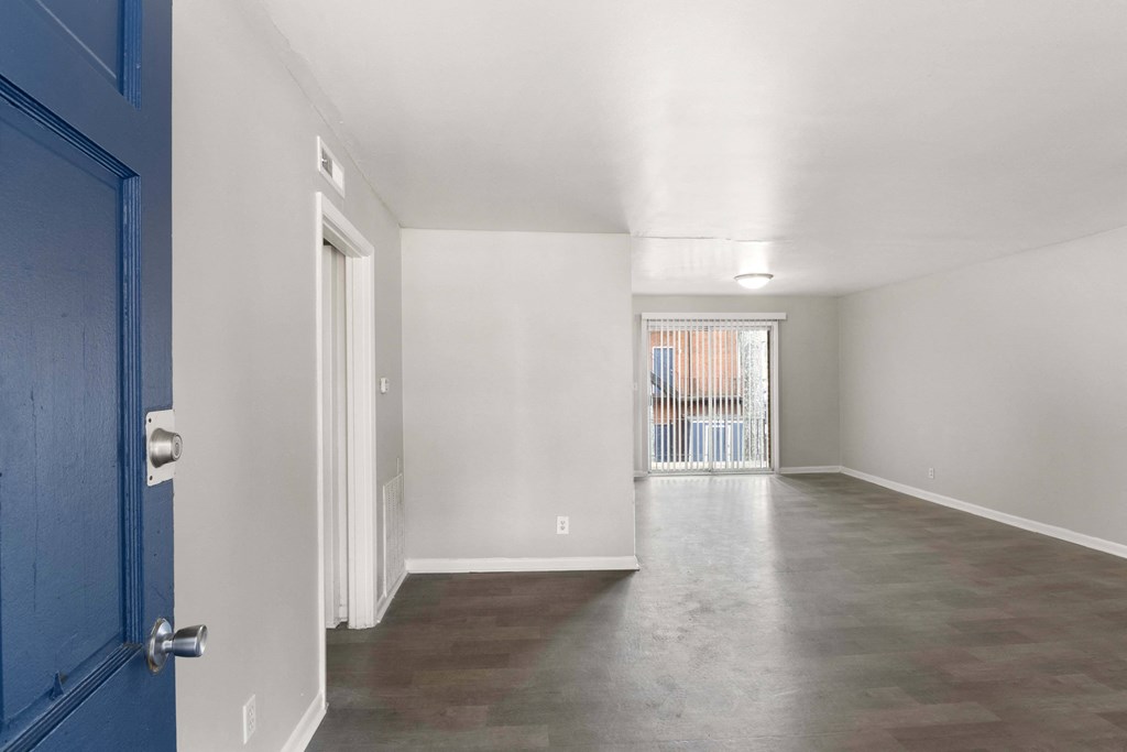 the living room and dining room of an apartment with a blue door