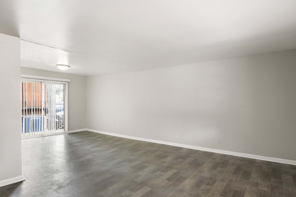 an empty living room with a sliding glass door to a balcony