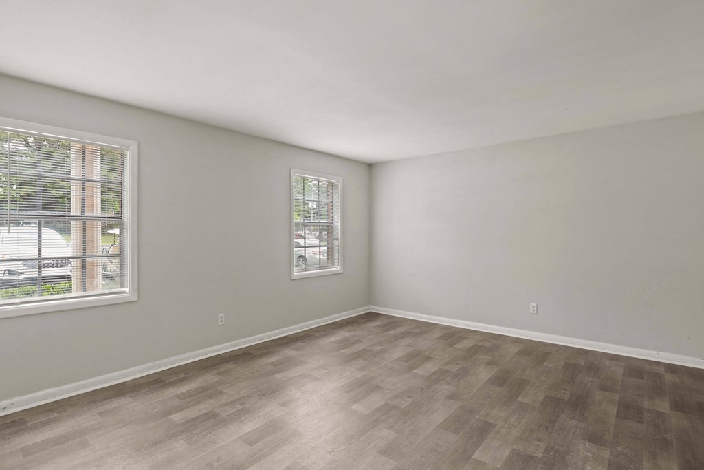 the living room of an apartment with wood flooring and a window