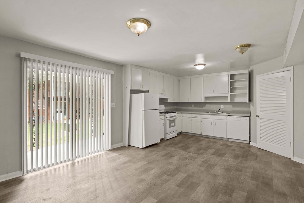 the living room and kitchen of a new home with white cabinets and a large window