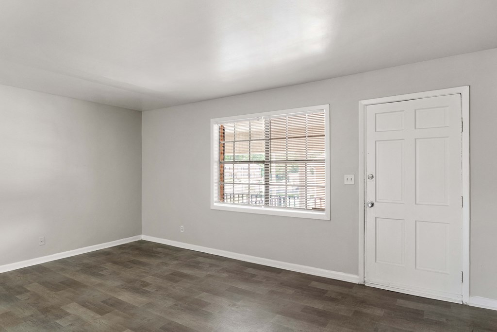 an empty bedroom with a window and a door