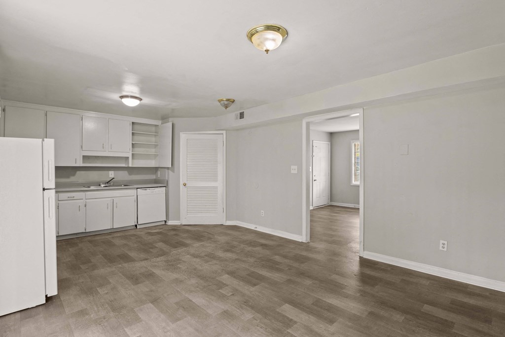 the living room and kitchen of an apartment with white cabinets and white appliances