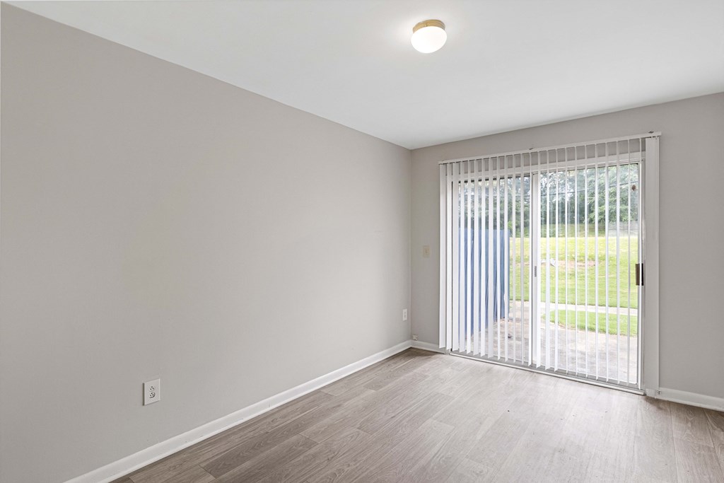 an empty living room with a sliding glass door to a yard