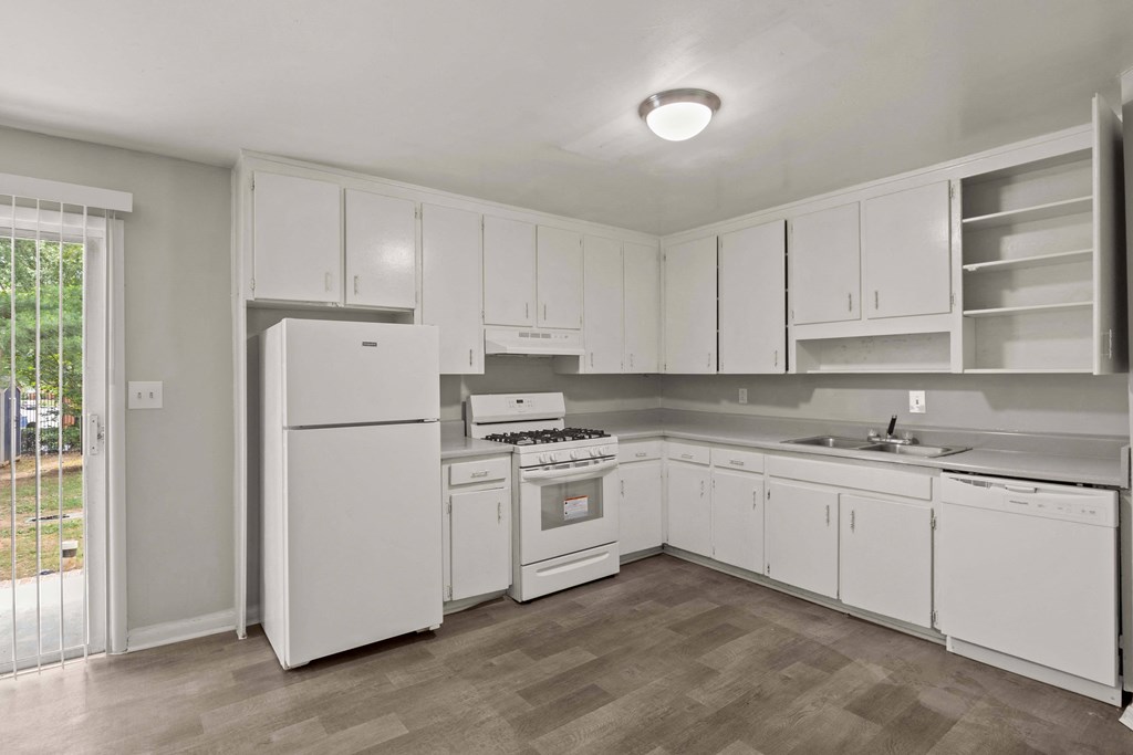 an empty kitchen with white cabinets and appliances and a white refrigerator