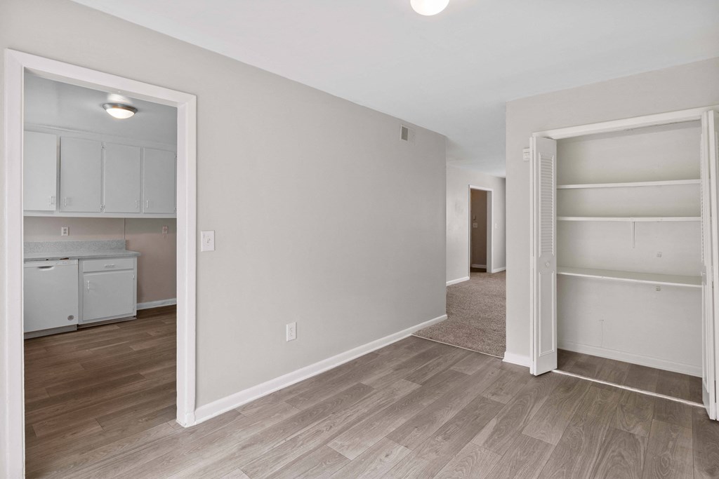 a bedroom with a closet and an open door to a bathroom and a kitchen