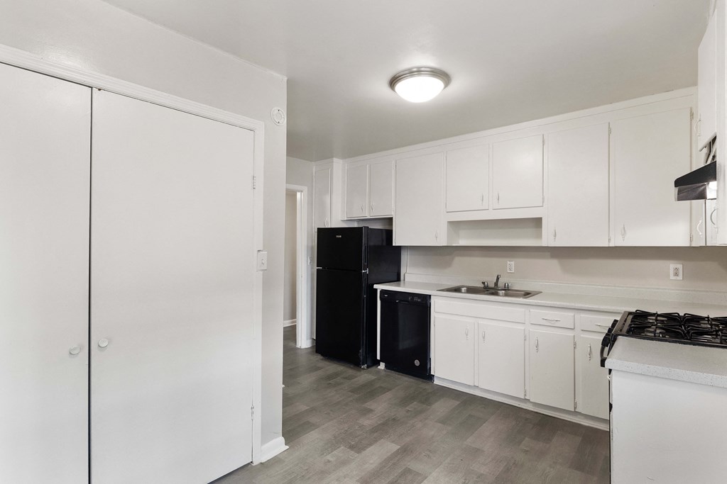 a kitchen with white cabinets and a black refrigerator