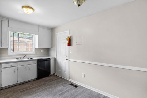 a kitchen with white walls and a black dishwasher and a window