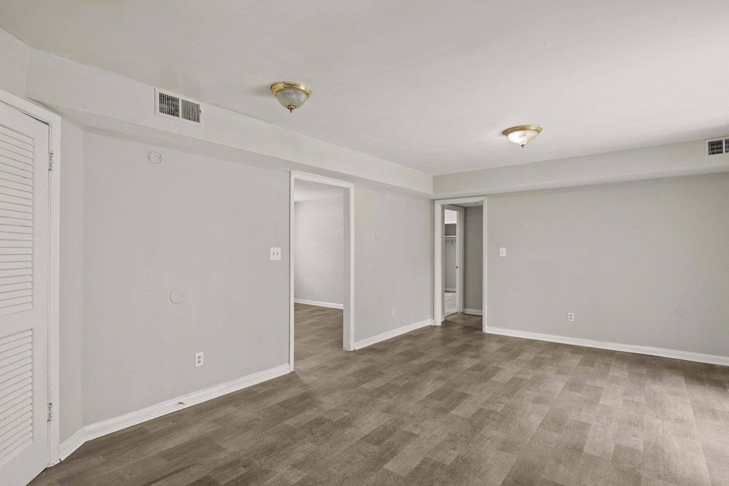 the living room of an empty apartment with white walls and wood flooring