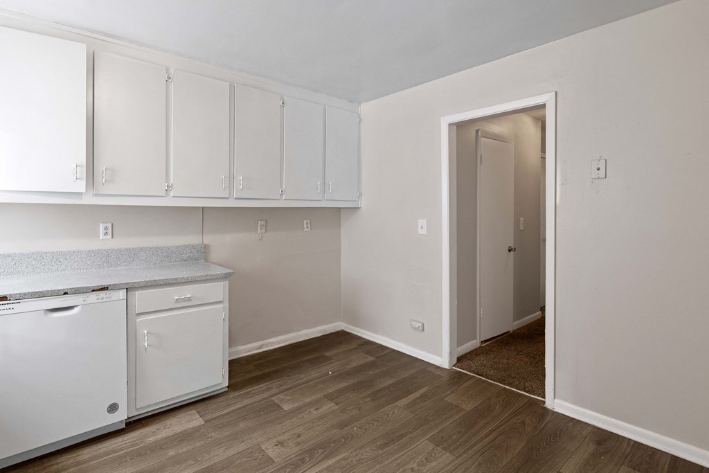 an empty kitchen with white cabinets and a door to a closet