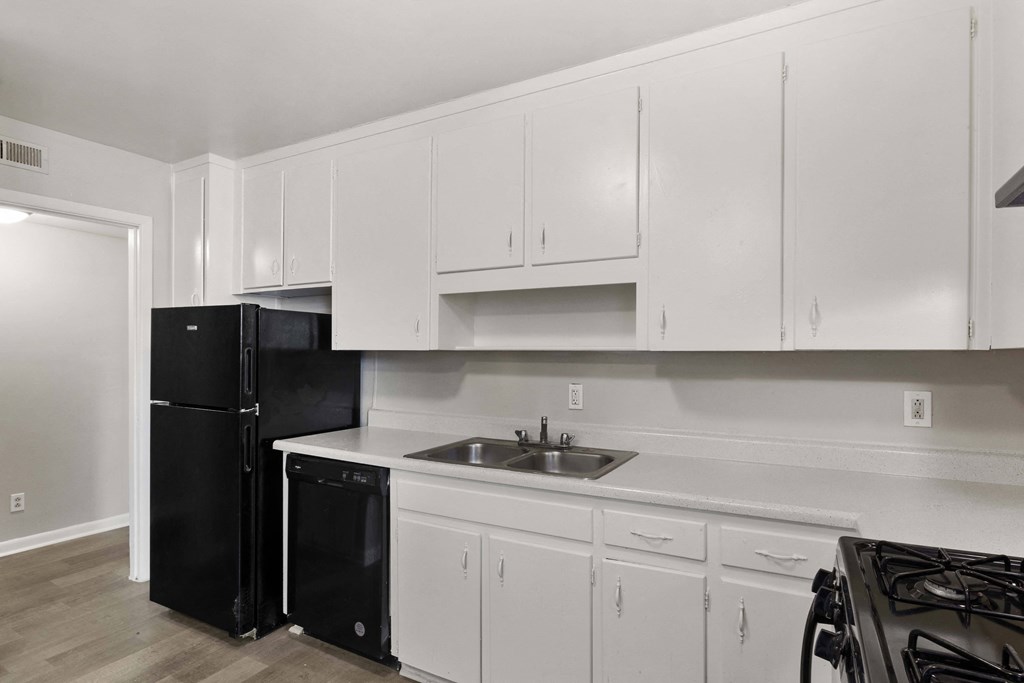a kitchen with white cabinets and a black refrigerator and sink