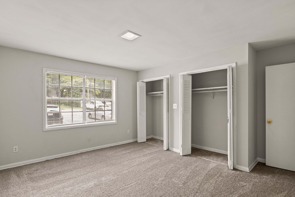 an empty bedroom with two closets and a window