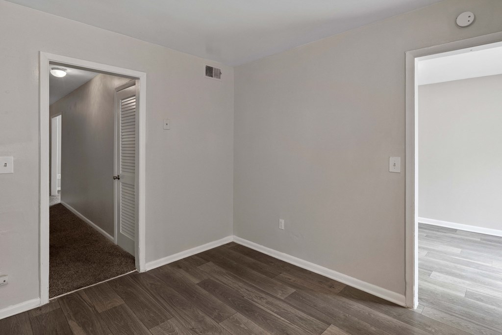an empty room with a hallway and a door to a bedroom
