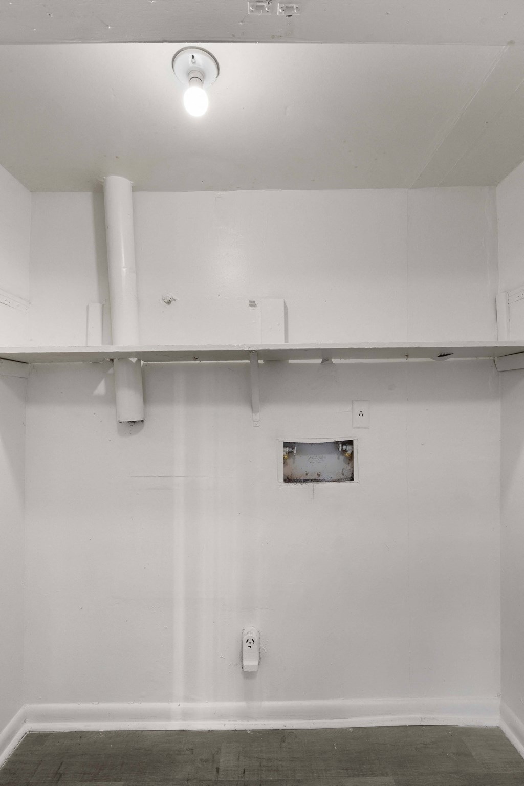 an empty room with white walls and a white pipe on the ceiling