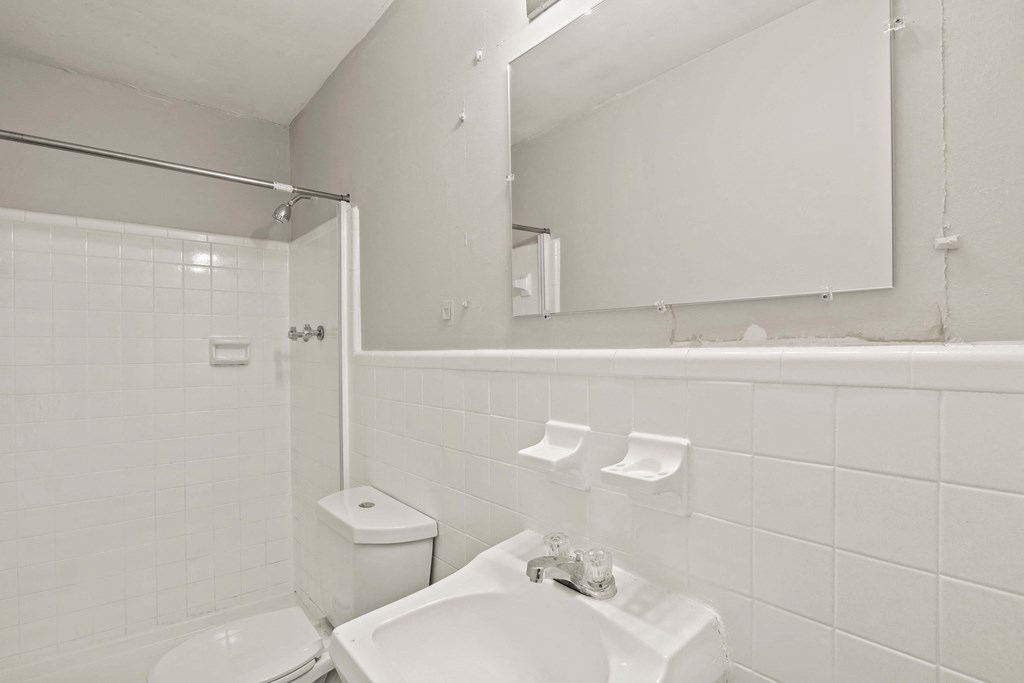 a white bathroom with a sink and a mirror and a toilet