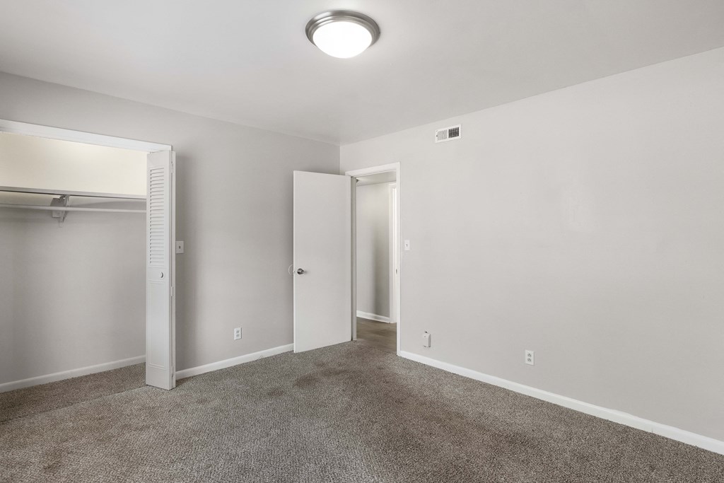 an empty living room with carpet and a closet