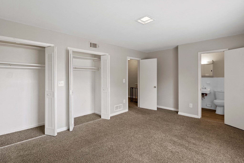 an empty bedroom with three closets and a bathroom