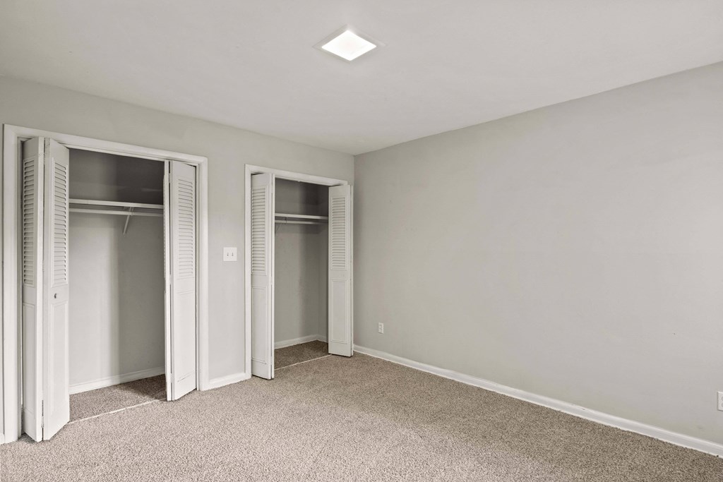 an empty bedroom with two closets and a carpeted floor