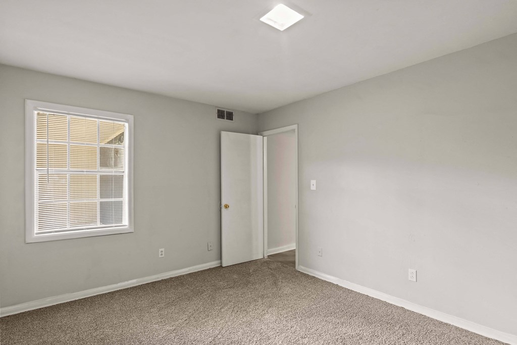 an empty bedroom with a window and a door to a closet