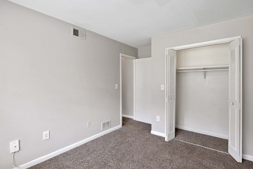 an empty bedroom with a closet and an open door