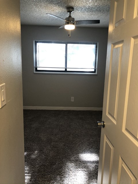 A room with a ceiling fan and a door.