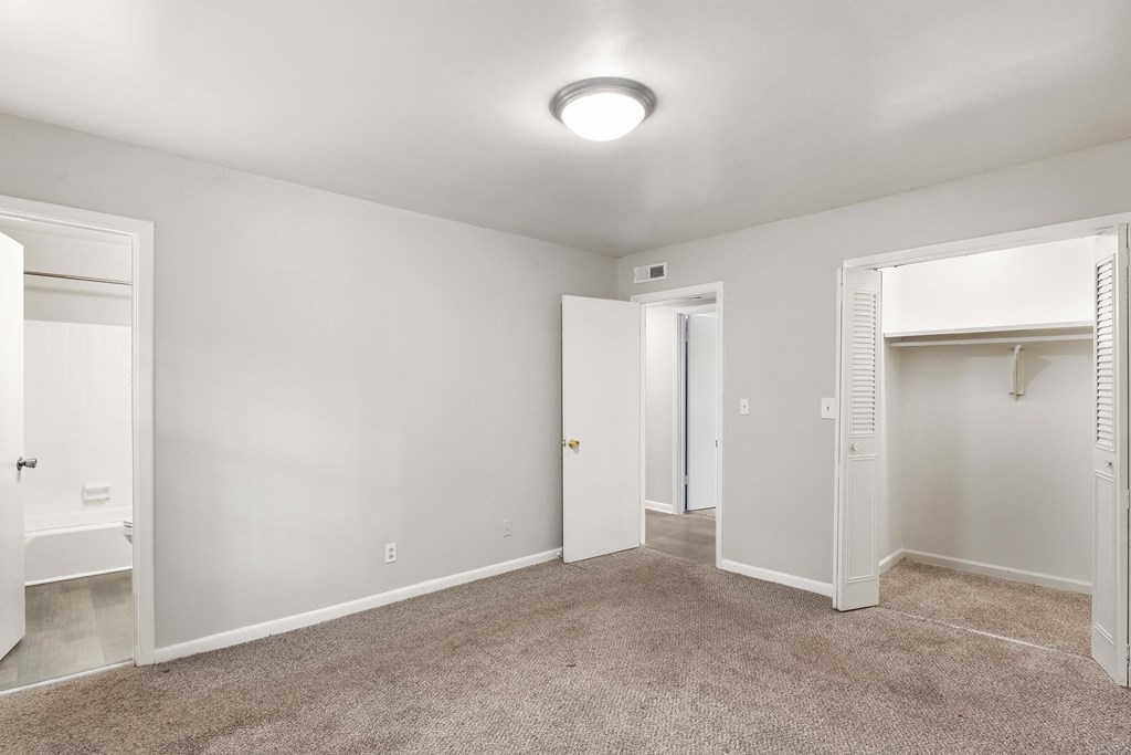 an empty bedroom with a closet and a door to a bathroom