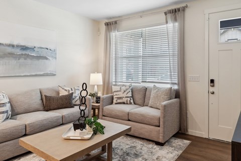 A living room with a couch, a chair, a coffee table, and a painting on the wall.