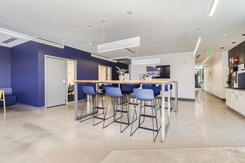 a bar with blue chairs and a counter in a room with a kitchen