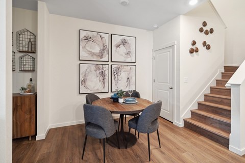 A dining room with a table set for two and a staircase in the background.