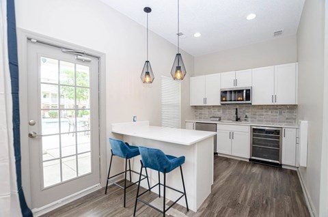 A kitchen with a white counter and blue chairs.