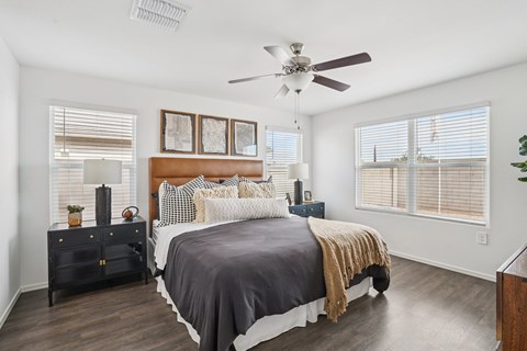 A bedroom with a bed, nightstand, and a ceiling fan.