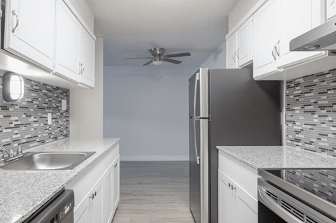A modern kitchen with a black refrigerator and white cabinets.