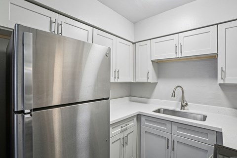 A kitchen with a stainless steel refrigerator and cabinets.